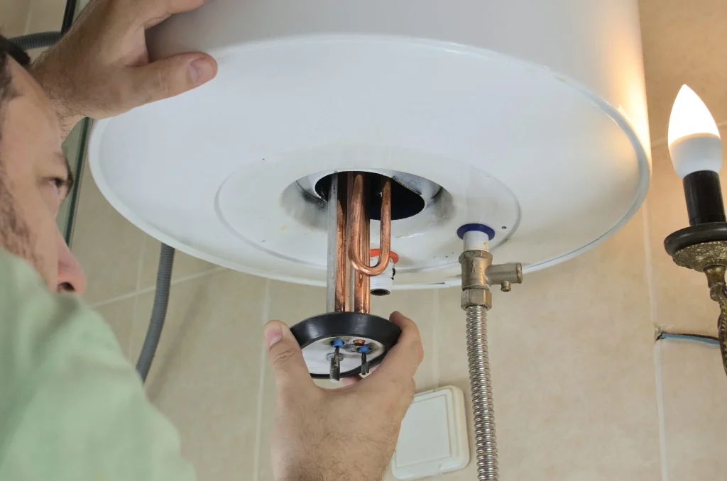 Plombier contrôlant la résistance et l'anode d'un chauffe-eau électrique